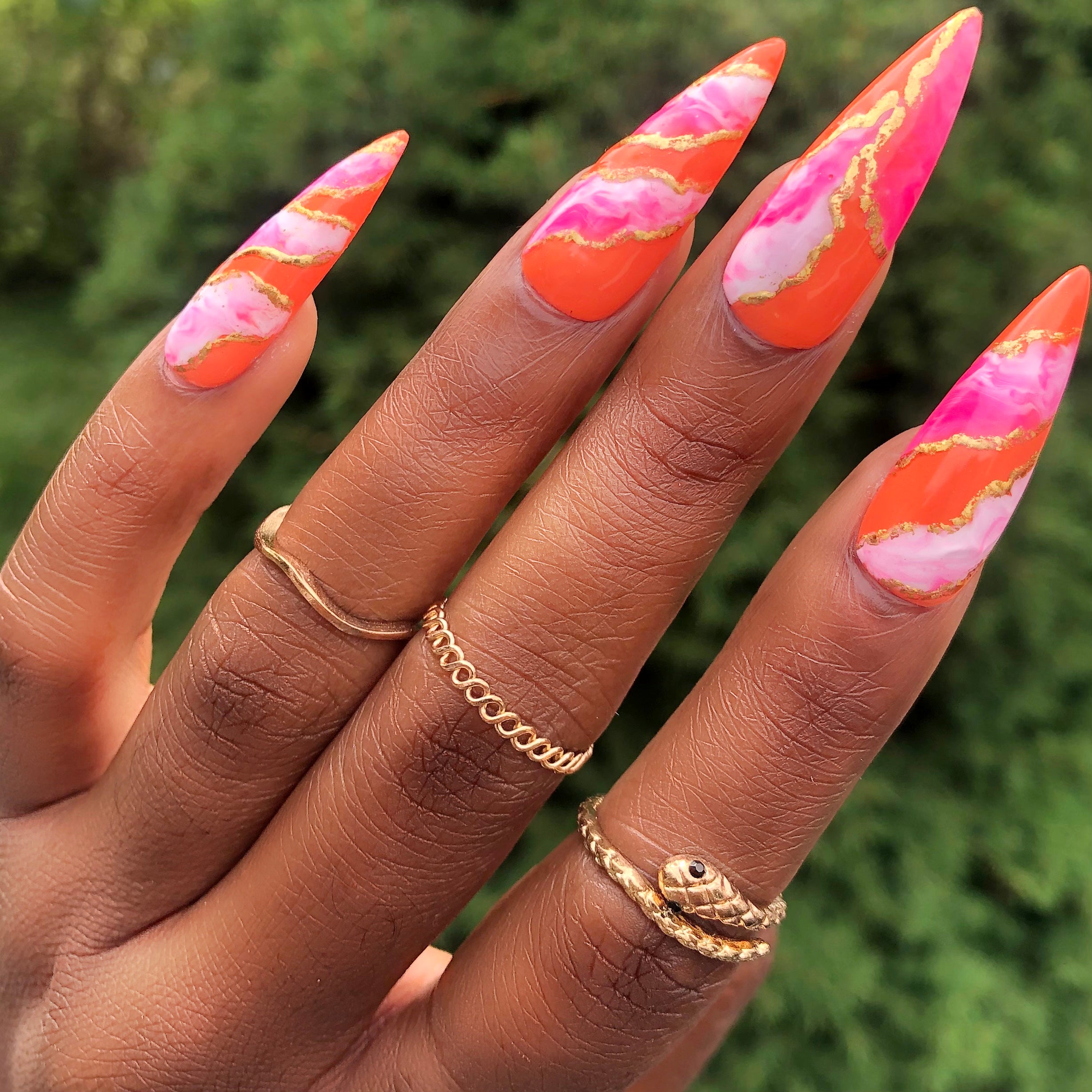 Marble pink nails design with an orange base using Mizz Frizzle. White gel polish mixed with pink marble. Gold knuckle rings.